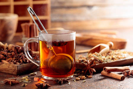 Christmas herbal tea with cinnamon, anise, and dried herbs. Herbal tea with spices in wooden dishes on an old brown table.の写真素材