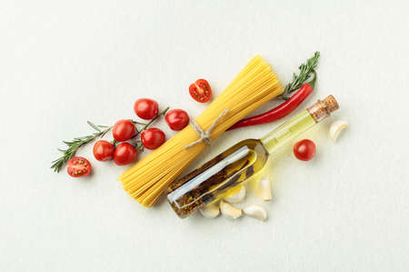 Spaghetti with bottle of olive oil, pepper, garlic, tomato, and rosemary, top view.