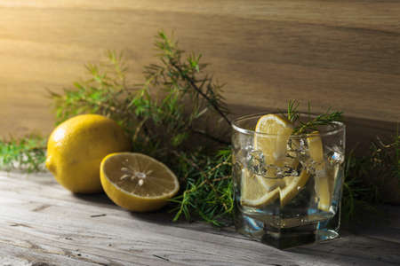 Cocktail with blue gin , tonic and lemon. Alcoholic drink with ice, lemon slices and juniper branch on a old wooden table.の写真素材