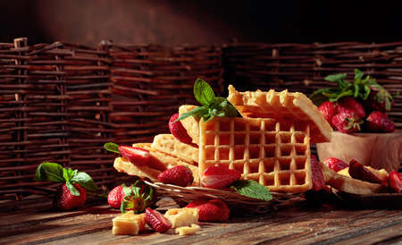 Waffles with strawberries and mint on a old wooden table.の写真素材
