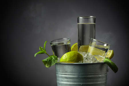 Strong alcoholic drink with lime and mint in a metal bucket with ice. Grey background with copy space.の写真素材