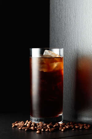 Iced coffee with coffee beans on a black table.