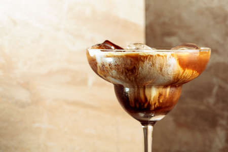Iced coffee with natural ice and cream on a brown background. Copy space.