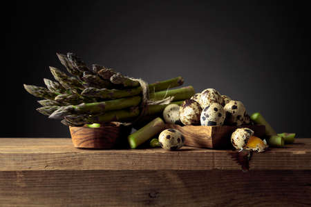 Fresh raw asparagus and quail eggs on an old wooden table. Copy space.の写真素材
