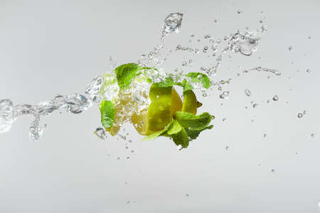 Fresh lime, mint, and ice in a splash on a white background.の写真素材