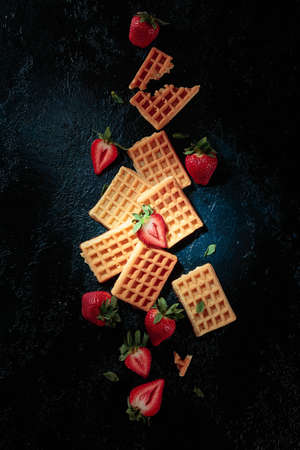 Waffles with fresh juicy strawberries on a dark blue background, view from above.の写真素材