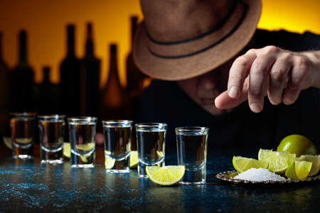 Man in the hat is drinking tequila with salt and lime slices. Selective focus.の写真素材