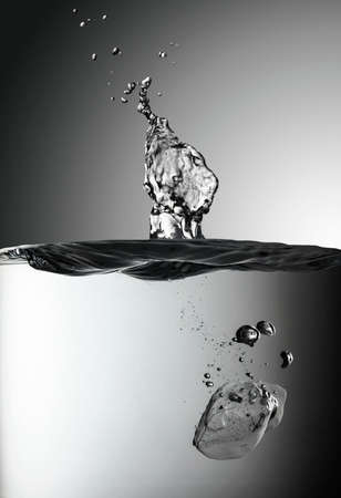 Ice piece drops into the water creating a splash. Selective focus.の写真素材