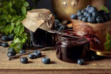 Blueberry jam with fresh berries on an old wooden table.の写真素材