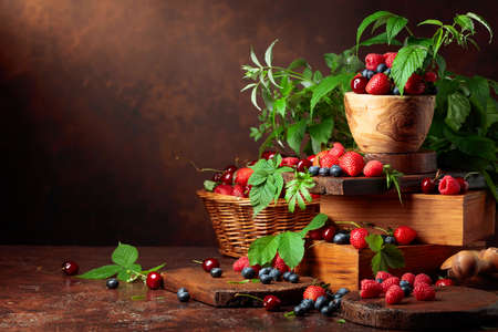 Assorted fresh berries with leaves. Strawberries, raspberries blueberries, and sweet cherries on an old vintage table.  Copy space.の写真素材