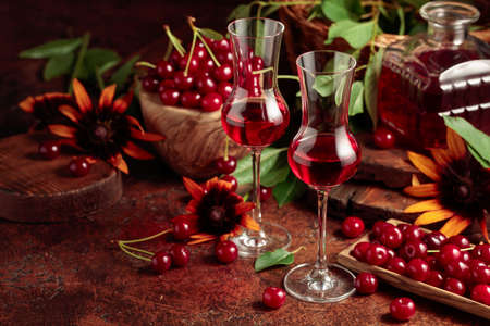 Cherry liquor and ripe juicy berries on a brown table.の写真素材