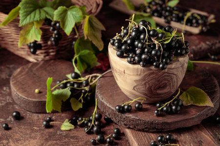 Ripe black currant in a wooden dish on a brown table.の写真素材