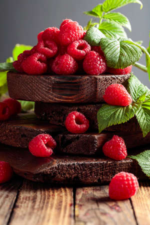 Fresh raspberries with leaves on an old wooden background.