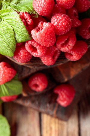 Fresh raspberries with leaves on an old wooden background. Selective focus.の写真素材