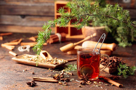 Christmas herbal tea with cinnamon, anise, and dried herbs. Herbal tea with juniper twig on an old brown table.の写真素材