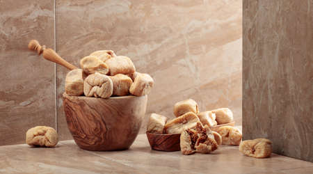 Sweet dried figs in a wooden dish on a kitchen ceramic table. Copy space.の写真素材