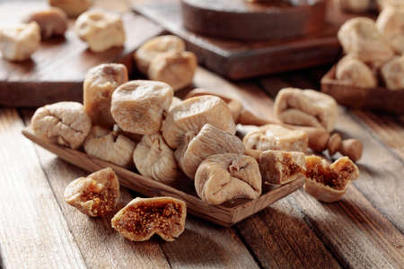Sweet dried figs in a wooden dish on a old wooden table.の写真素材
