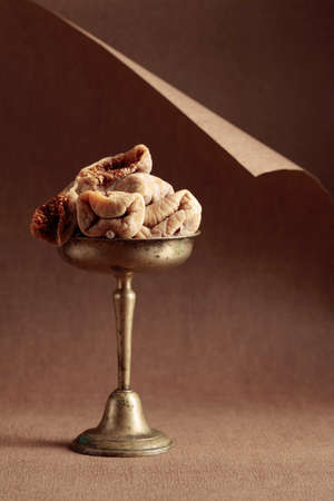 Dried figs in an old brass dish on a brown background.の写真素材