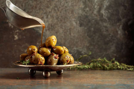 Spicy green olives are poured with olive oil. Copy space.の写真素材