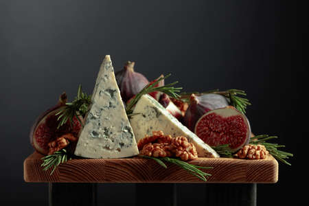 Blue cheese with figs, walnuts, and rosemary on a wooden table.の写真素材