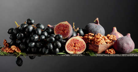 Figs, walnuts and blue grapes on a black background. Copy space.の写真素材