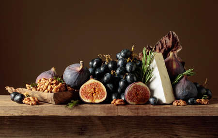Cheese brie with figs, walnuts, and blue grapes on a wooden table. Copy space.の写真素材