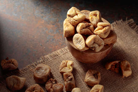 Dried figs in an old woodew dish on a burlap background.の写真素材