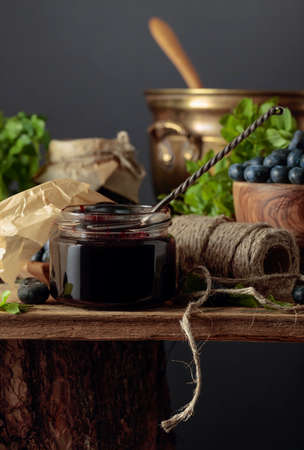 Blueberry jam with fresh berries on an old wooden table.