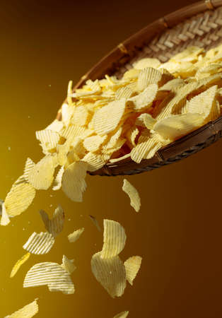 Falling potato chips on a yellow background. Copy space.の写真素材