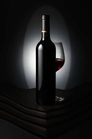 Glass and bottle of red wine on a dark background.の写真素材