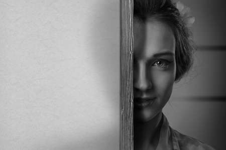 Happy young beautiful woman behind the paper screen, free space for your text. Black and white.の写真素材