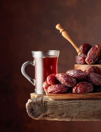 Tea and dried dates on a old wooden table.の写真素材