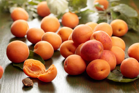 Fresh juicy apricots with leaves on a wooden table in the garden.の写真素材