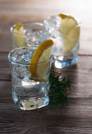 Gin with lemon, juniper and ice on a old wooden table.の写真素材