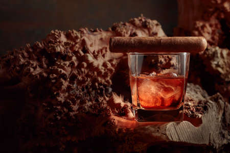 Whiskey wit ice and cigar on an old dried snag. Copy space.の写真素材