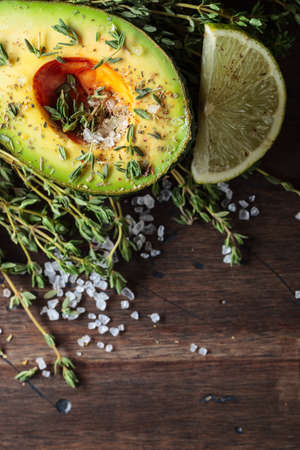 Avocado with lime, thyme, and sea salt on a old wooden table.の写真素材