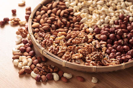 Various nuts in an old wooden dish on a wooden kitchen table. Selective focus.