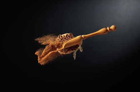 Cinnamon powder is poured out of the wooden spoon. The ground cinnamon and cinnamon sticks, tied...