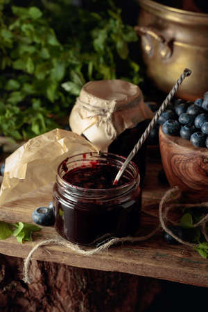 Blueberry jam with fresh berries on an old wooden table.