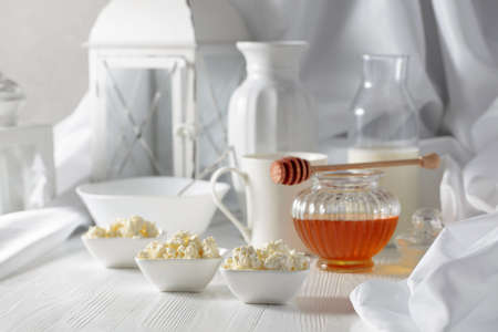 Fresh homemade cottage cheese or ricotta with honey on a white wooden table.