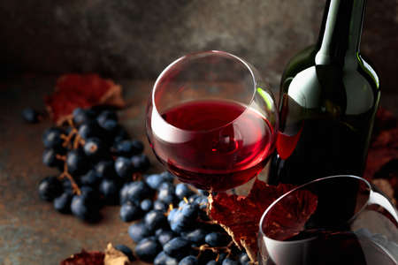 Red wine with blue grapes on vintage background.の写真素材