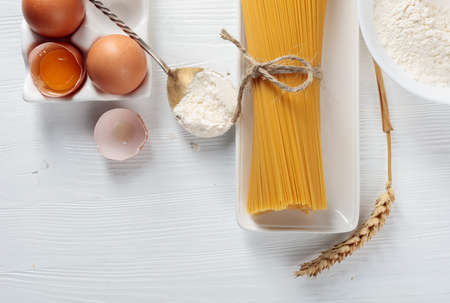 Spaghetti with ingredients on a white wooden table. Top view.の写真素材