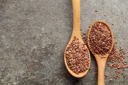 Wooden spoons with flaxseed on a stone background. Top view with copy space.の写真素材