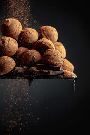 Delicious chocolate truffles sprinkled with cocoa powder on a black background.の写真素材