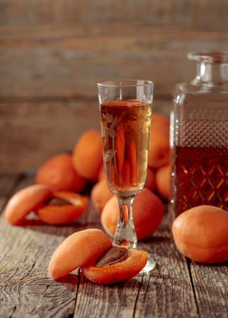 Apricot liquor and fresh apricots on a old wooden table. Wine and juicy fruits on wooden background.の写真素材