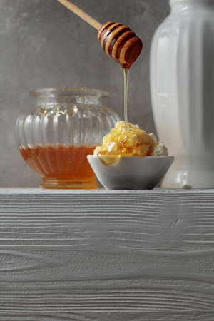 Fresh homemade cottage cheese or ricotta with honey on a white wooden table. Healthy organic breakfast. Copy space.の写真素材