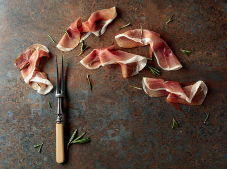 Prosciutto with rosemary on vintage background. Traditional Mediterranean snack. Top view.の写真素材