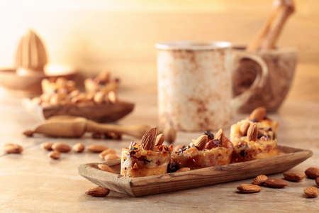 Small cakes with almonds, raisins, and honey on a brown table.