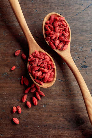 Dried goji berries in wooden spoons on an old wooden table. Copy space.