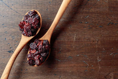 Raisins in wooden spoons on an old wooden table. Top view.